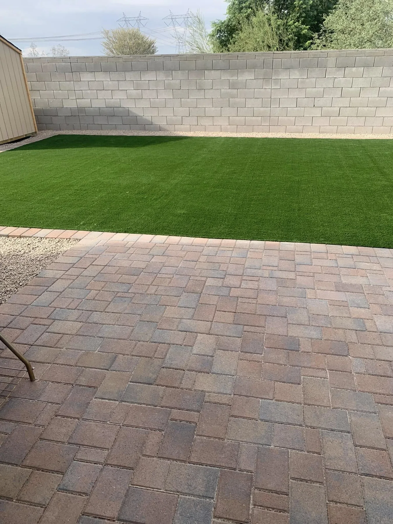 Paver courtyard and artificial turf in a finished backyard